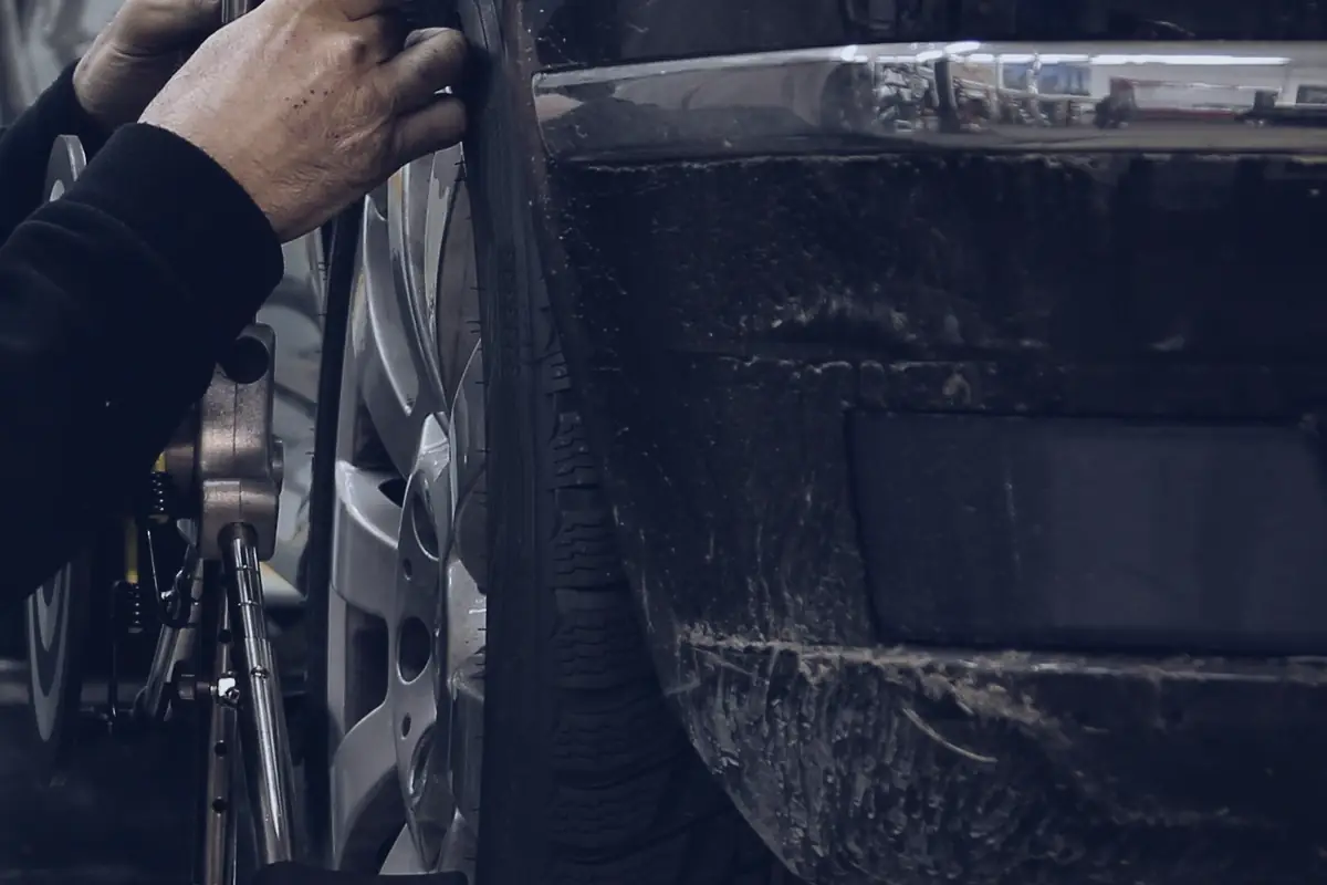 Hands on a tyre, with a wheel alignment clamp fitted to its alloy rim