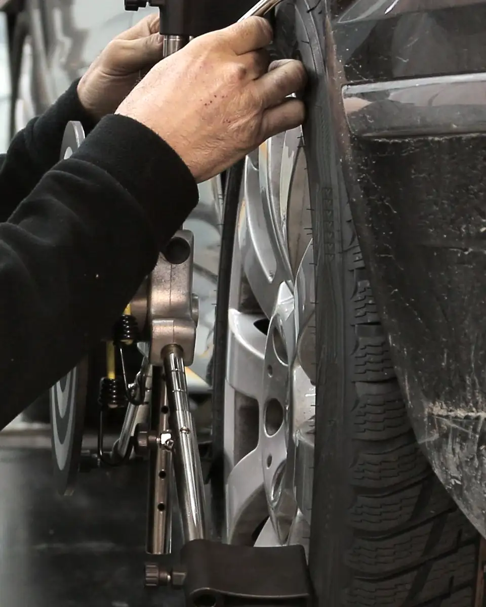 Hands fitting a wheel-alignment clamp to a car’s wheel