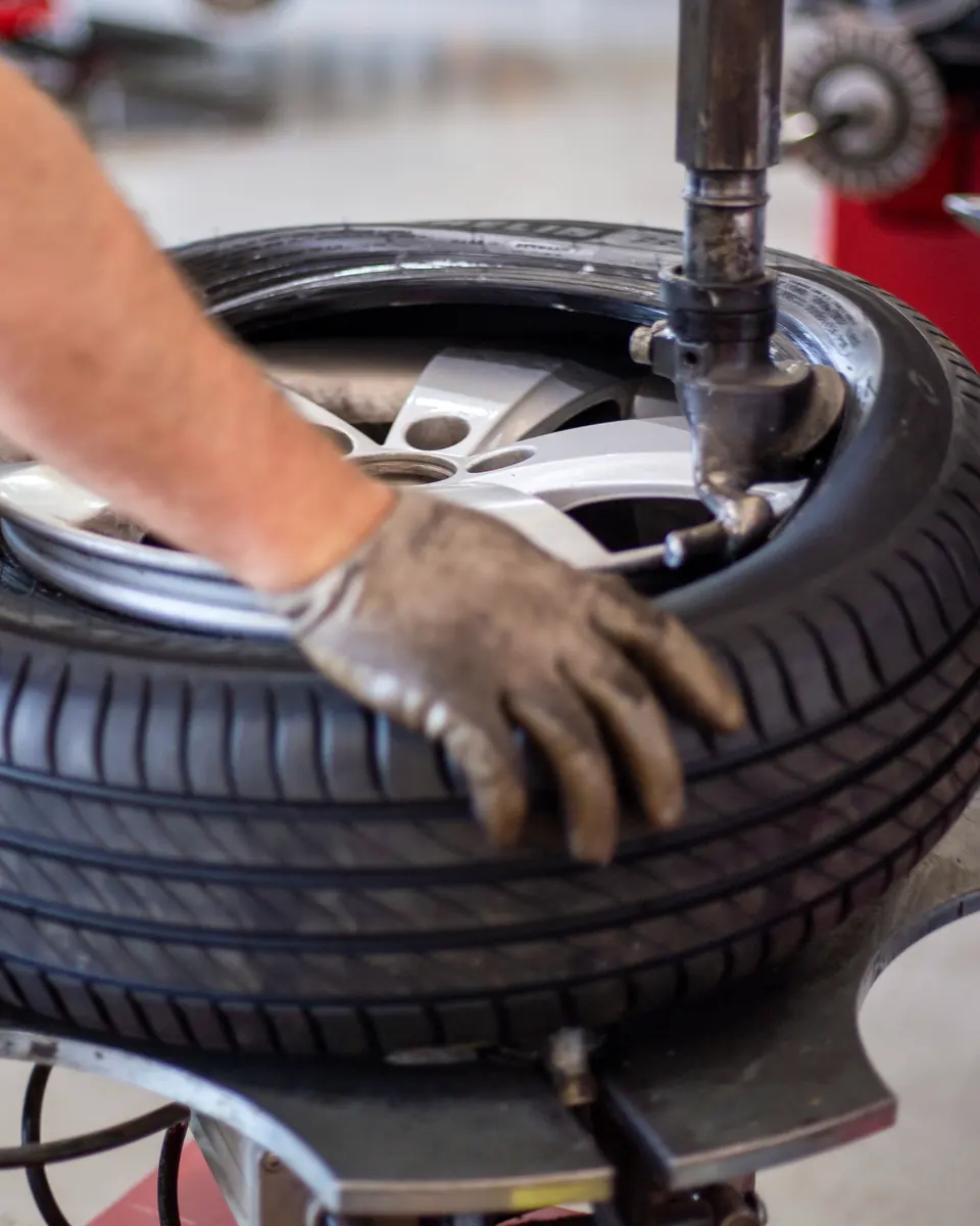 A gloved hand steadies a tyre on a tyre-changing machine