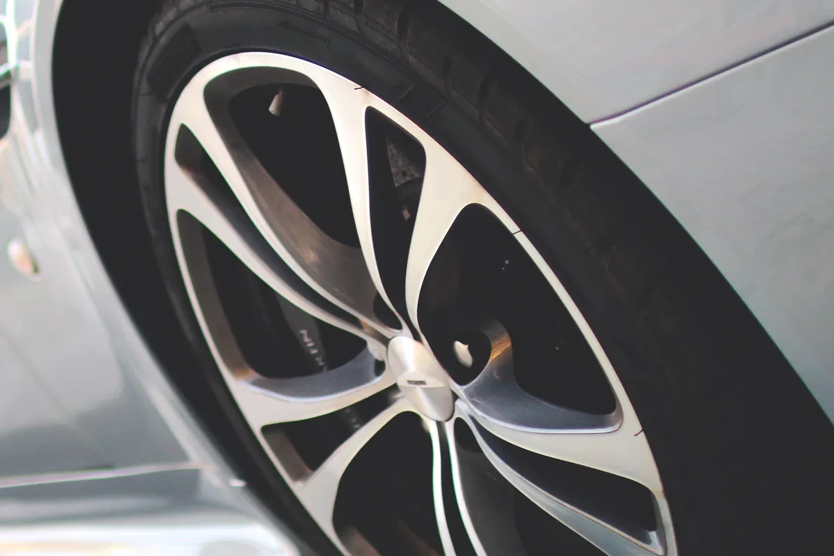 Close-up of a silver multi-spoke alloy wheel and tyre on a pale grey car