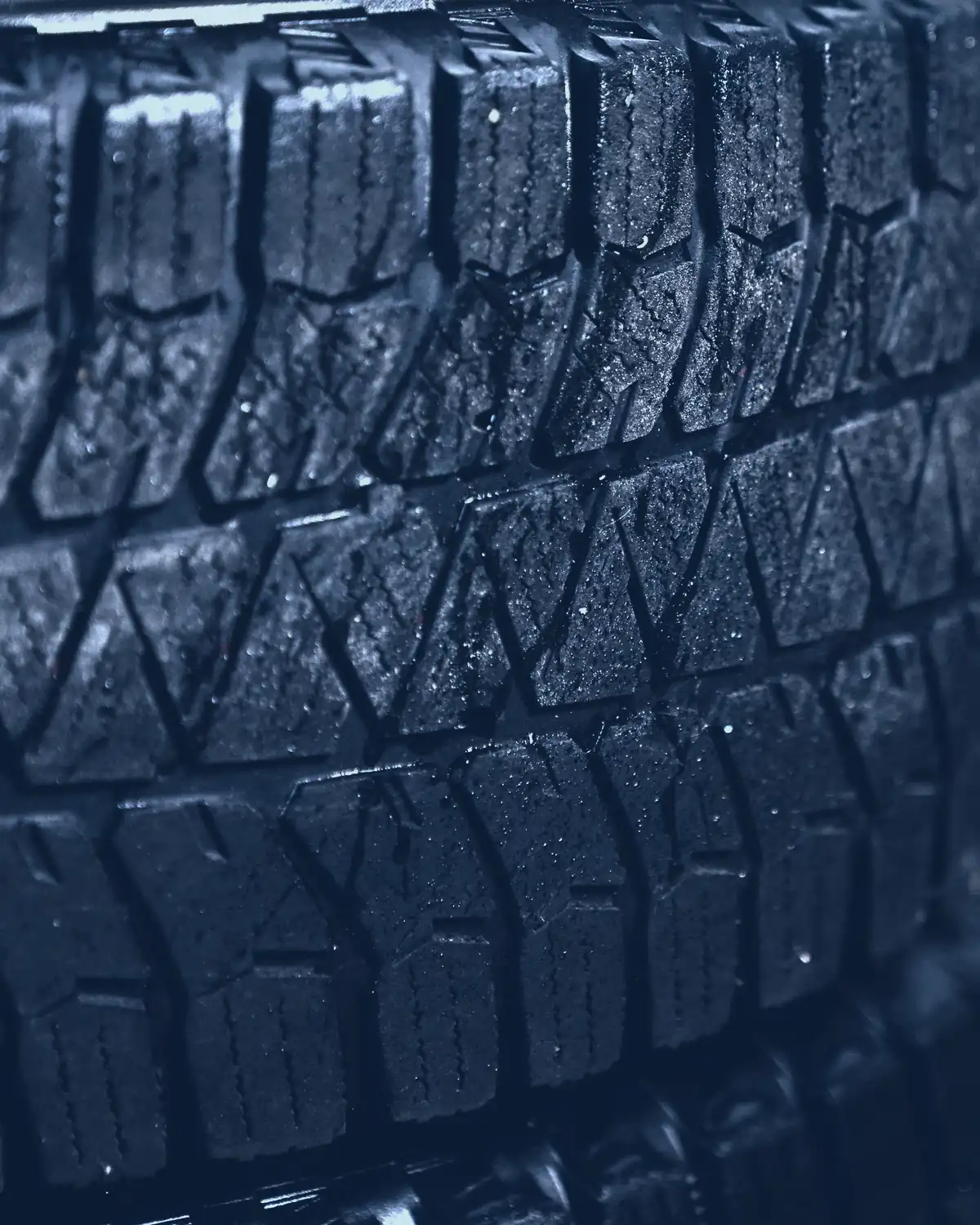Close-up of rows of tyre tread blocks, glinting in low light